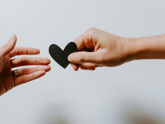 person-reaching-black-heart-cutout-paper.jpg person reaching black heart cutout paper
